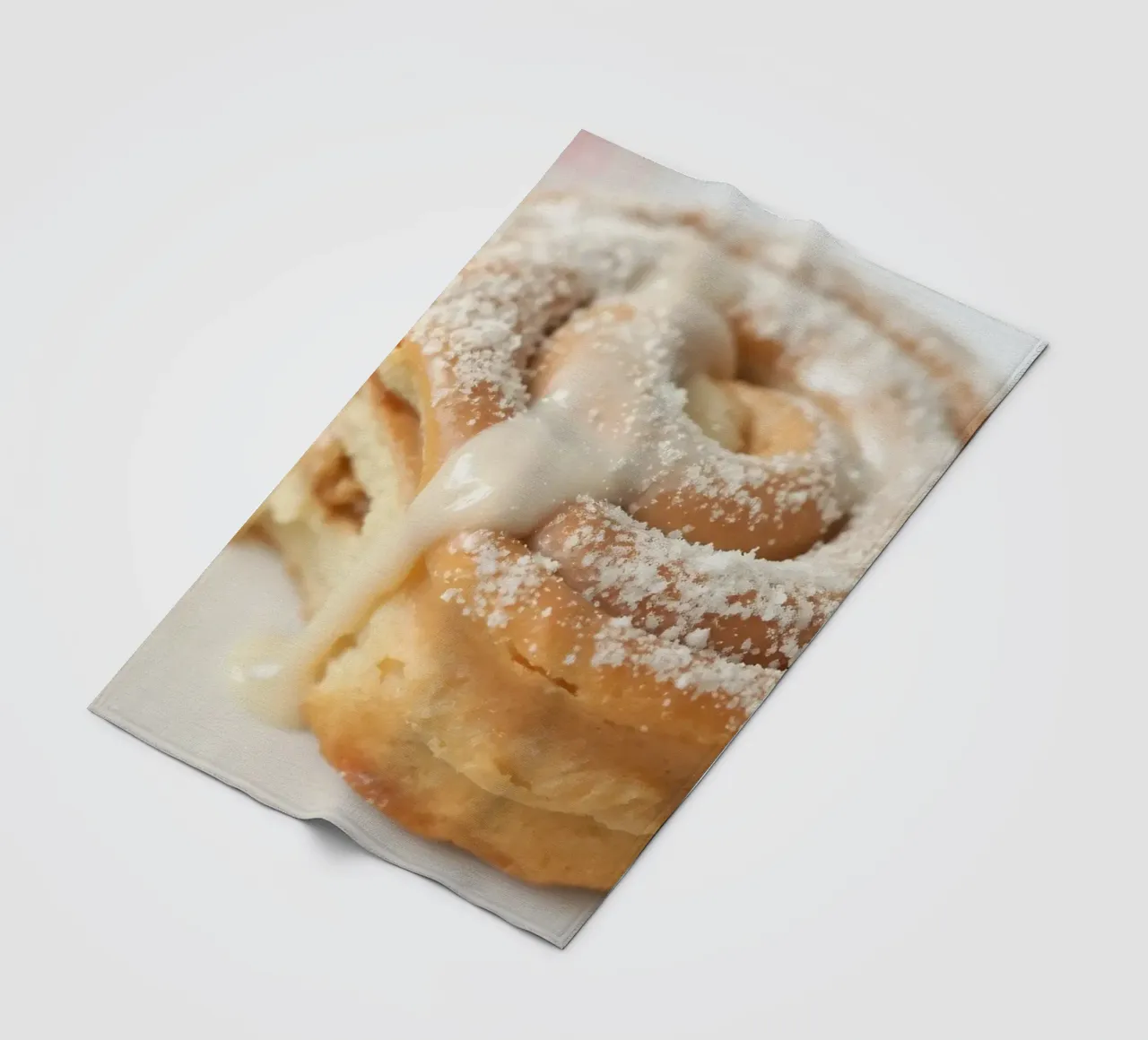 Warm cinnamon roll with cream icing and powdered sugar on a fleece blanket by DesignDoodle