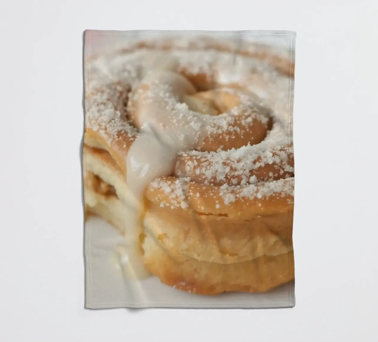 Warm cinnamon roll with cream icing and powdered sugar on a fleece blanket by DesignDoodle