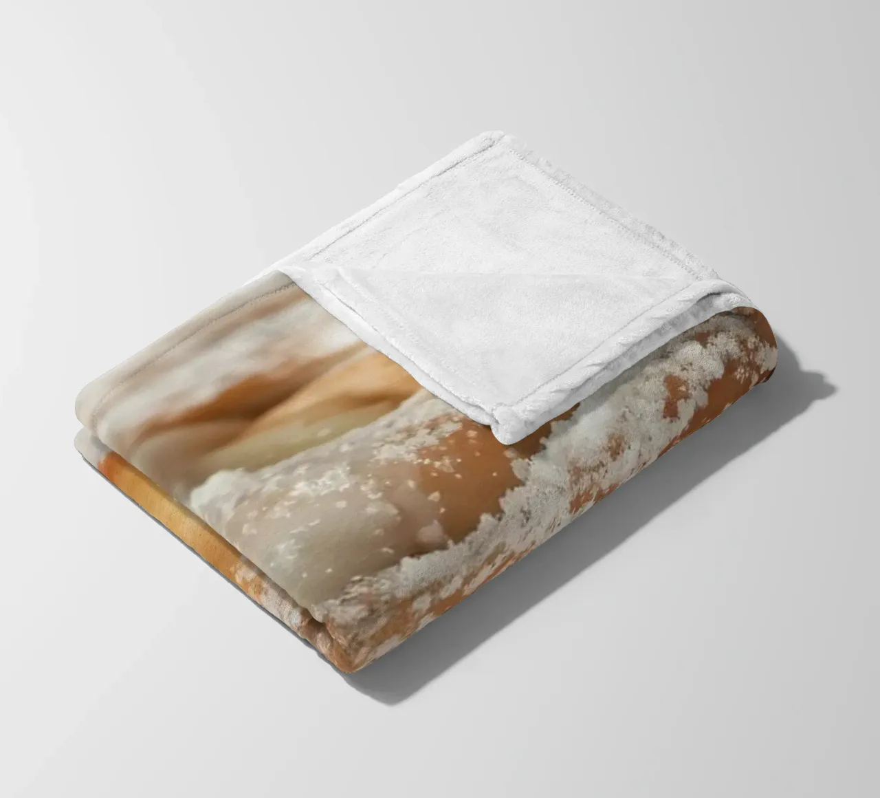 Warm cinnamon roll with cream icing and powdered sugar on a fleece blanket by DesignDoodle