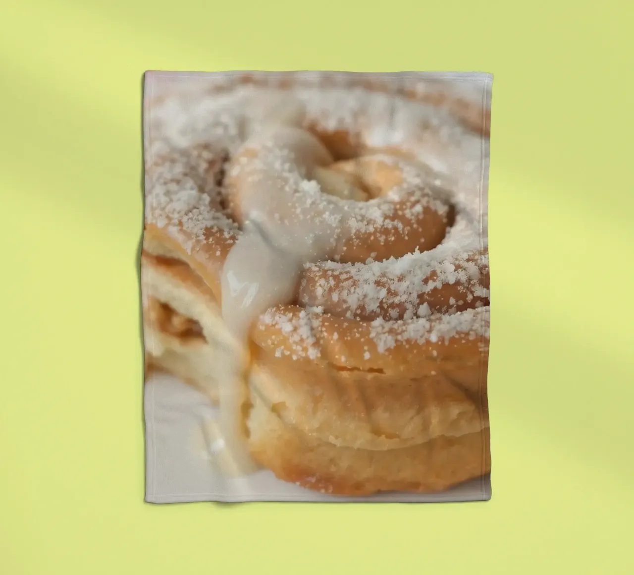 Warm cinnamon roll with cream icing and powdered sugar on a fleece blanket by DesignDoodle