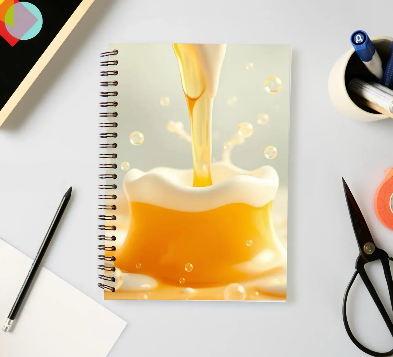 Golden liquid pouring into a frothy mug, capturing the essen spiral notebook by DesignDoodle