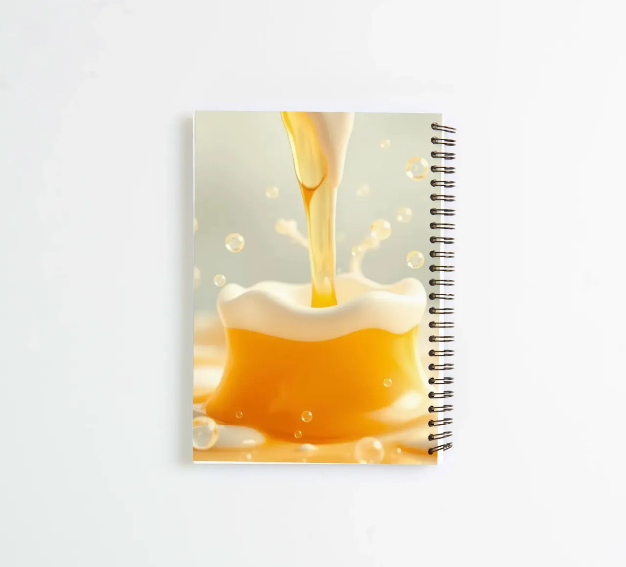 Golden liquid pouring into a frothy mug, capturing the essen spiral notebook by DesignDoodle