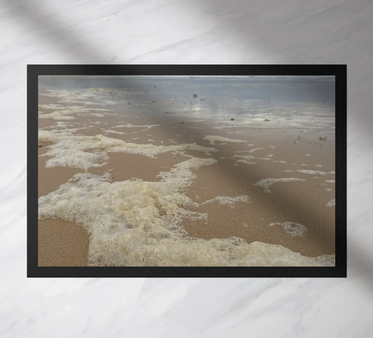 Burbujas de espuma bajo un cielo nublado en la playa felpudo de byrieneke
