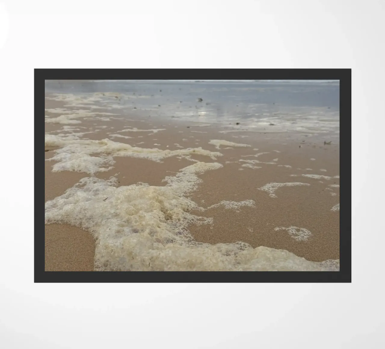 Burbujas de espuma bajo un cielo nublado en la playa felpudo de byrieneke