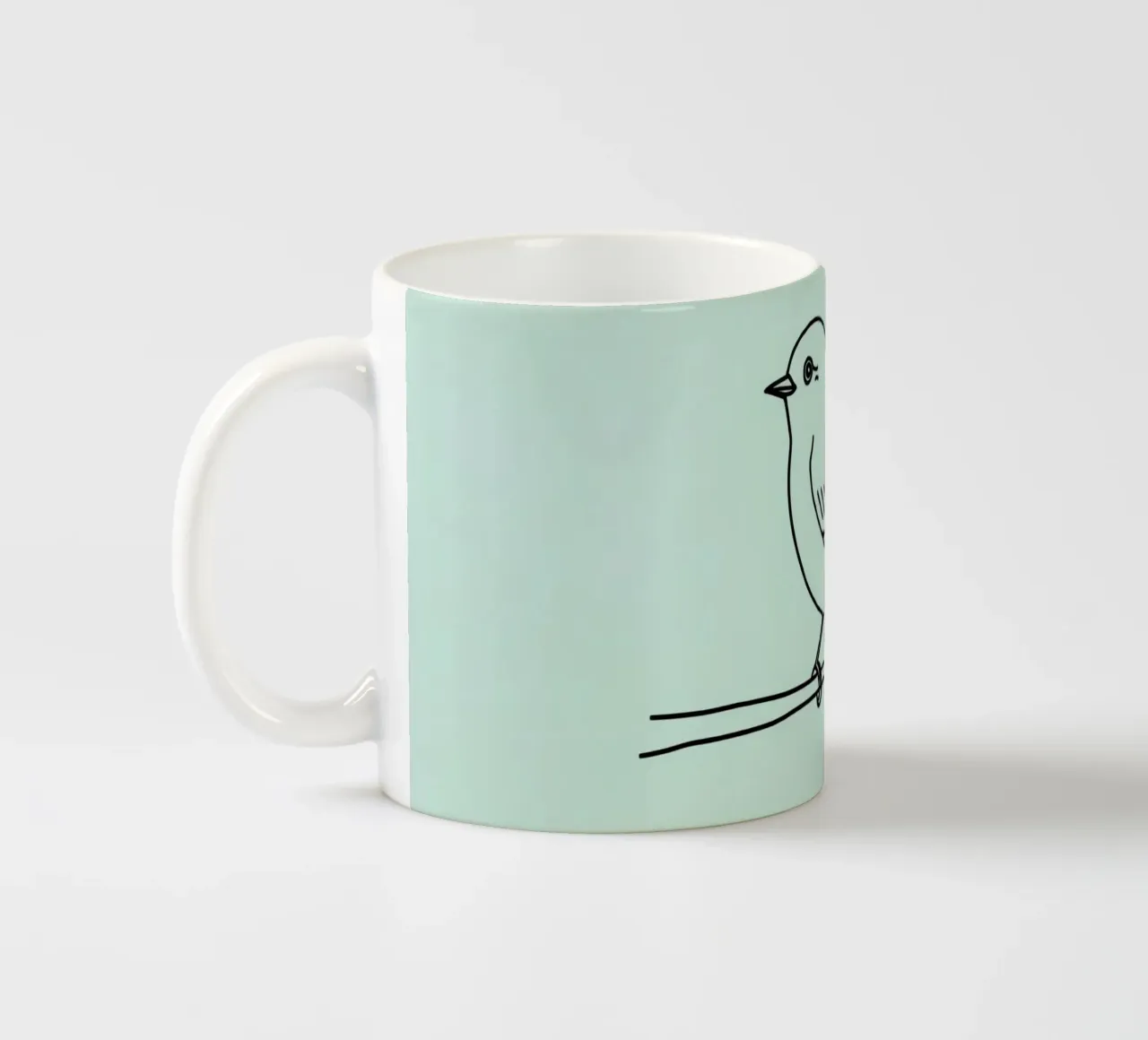 un piccolo uccello appollaiato su un ramo sfondo verde chiaro tazza in ceramica da DesignDoodle