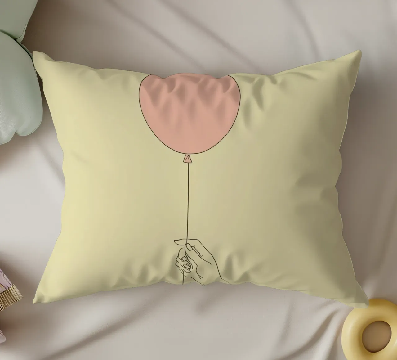 Mano che tiene un palloncino rosa su un'opera d'arte giallo tenue cuscino da DesignDoodle