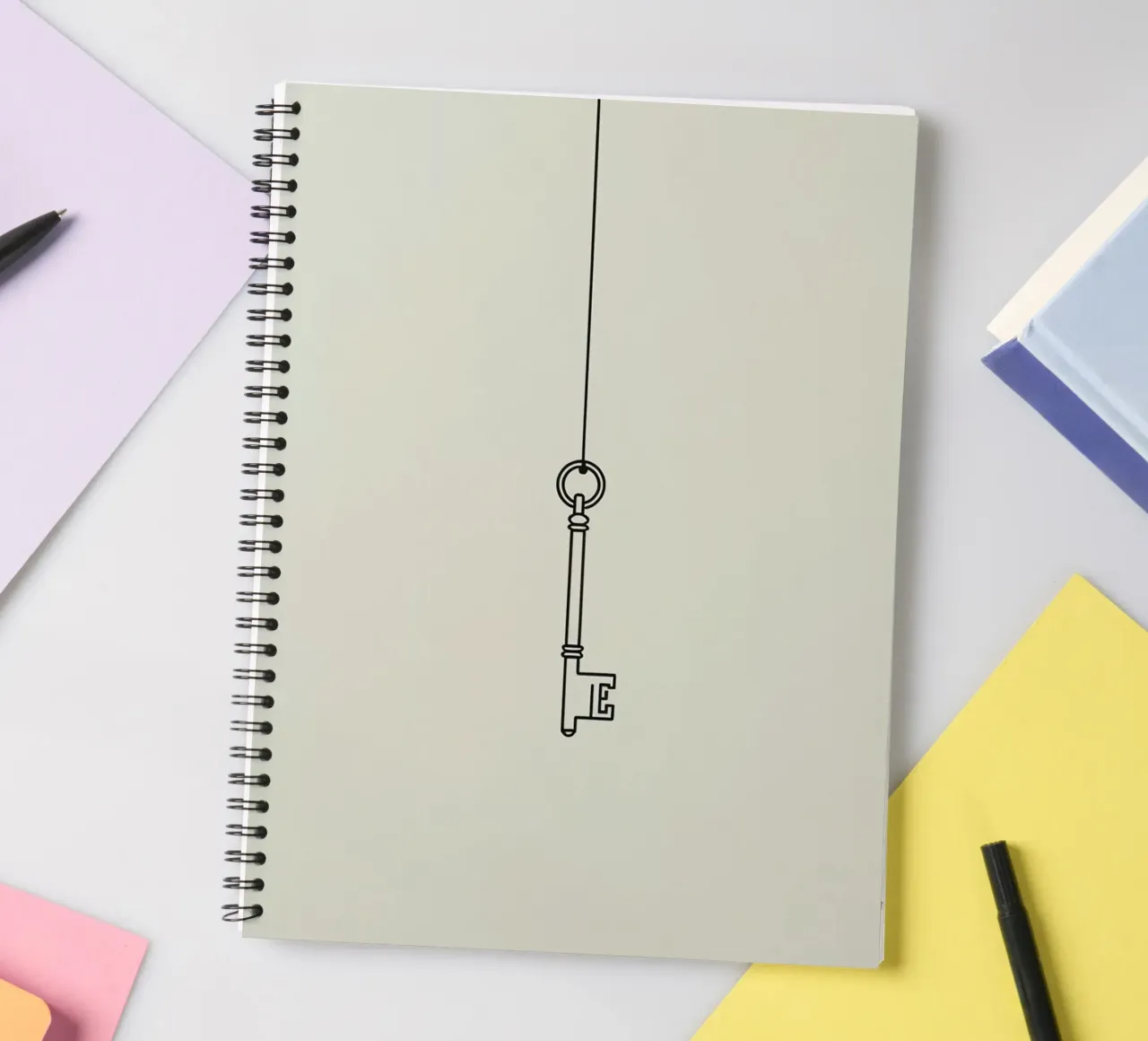 Key hanging from a string against a light backdrop spiral notebook by DesignDoodle