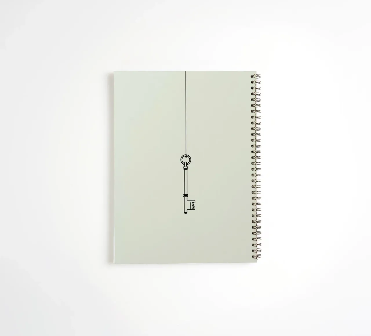 Key hanging from a string against a light backdrop spiral notebook by DesignDoodle