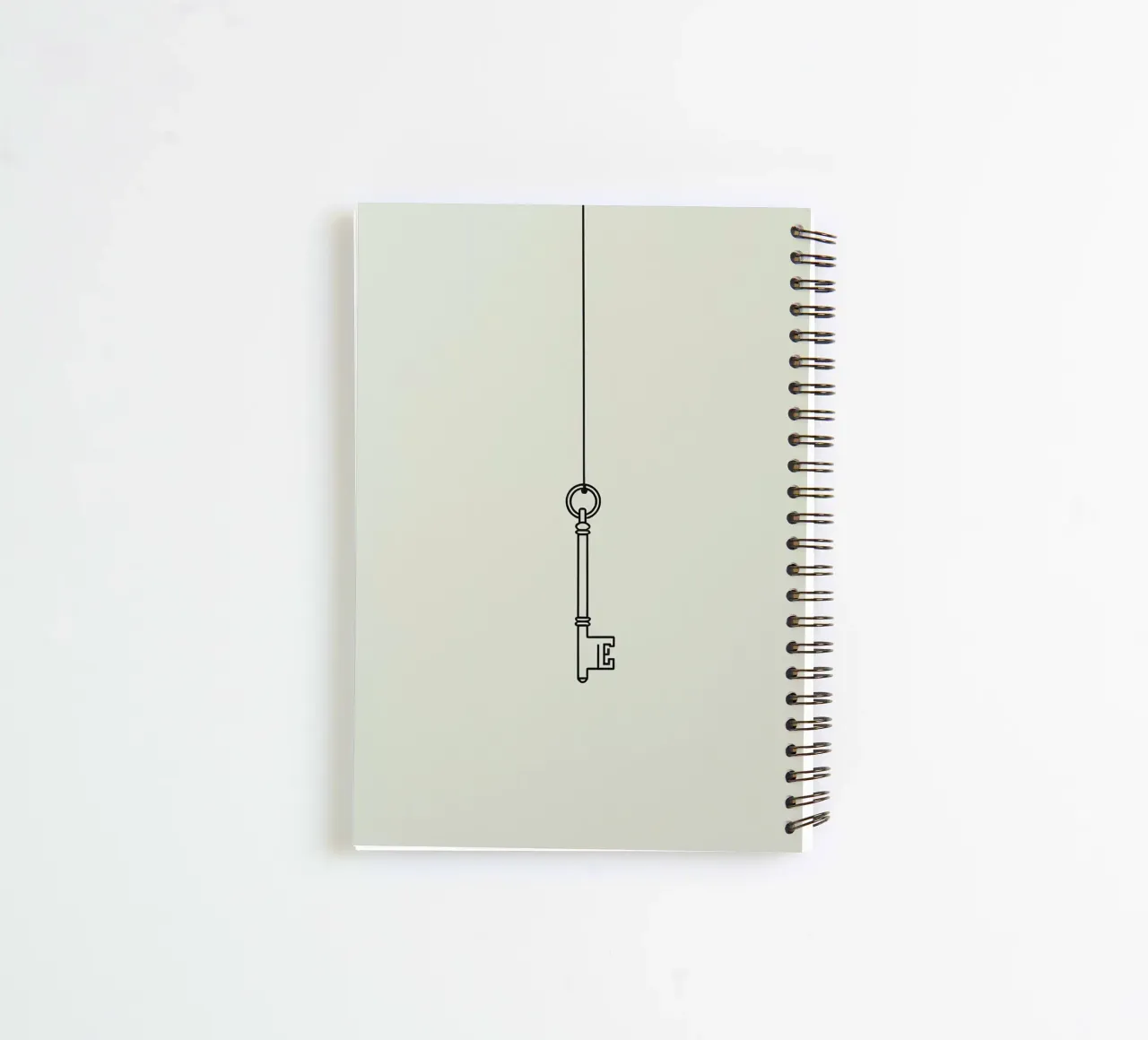 Key hanging from a string against a light backdrop spiral notebook by DesignDoodle