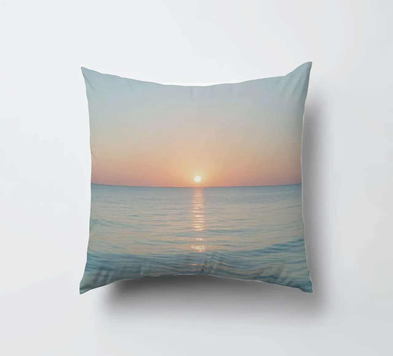 Sunset over calm ocean waters with pastel hues reflecting decorative cushion by DesignDoodle