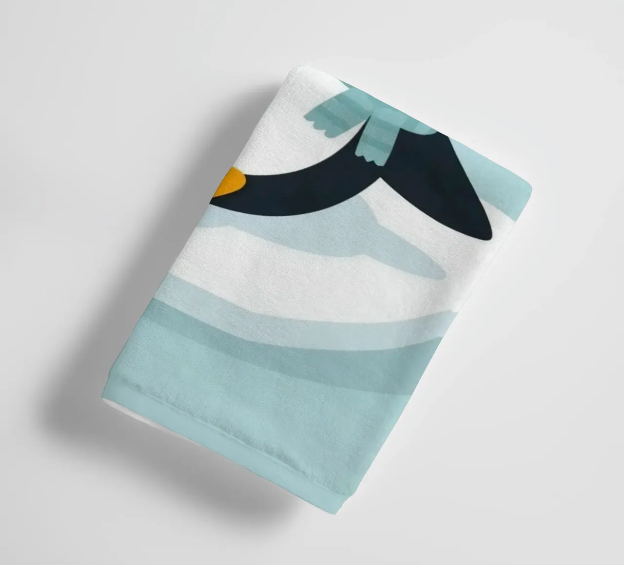 Un mignon pingouin avec une écharpe bleu clair se repose sur une glace blanche. serviette de bain de DesignDoodle