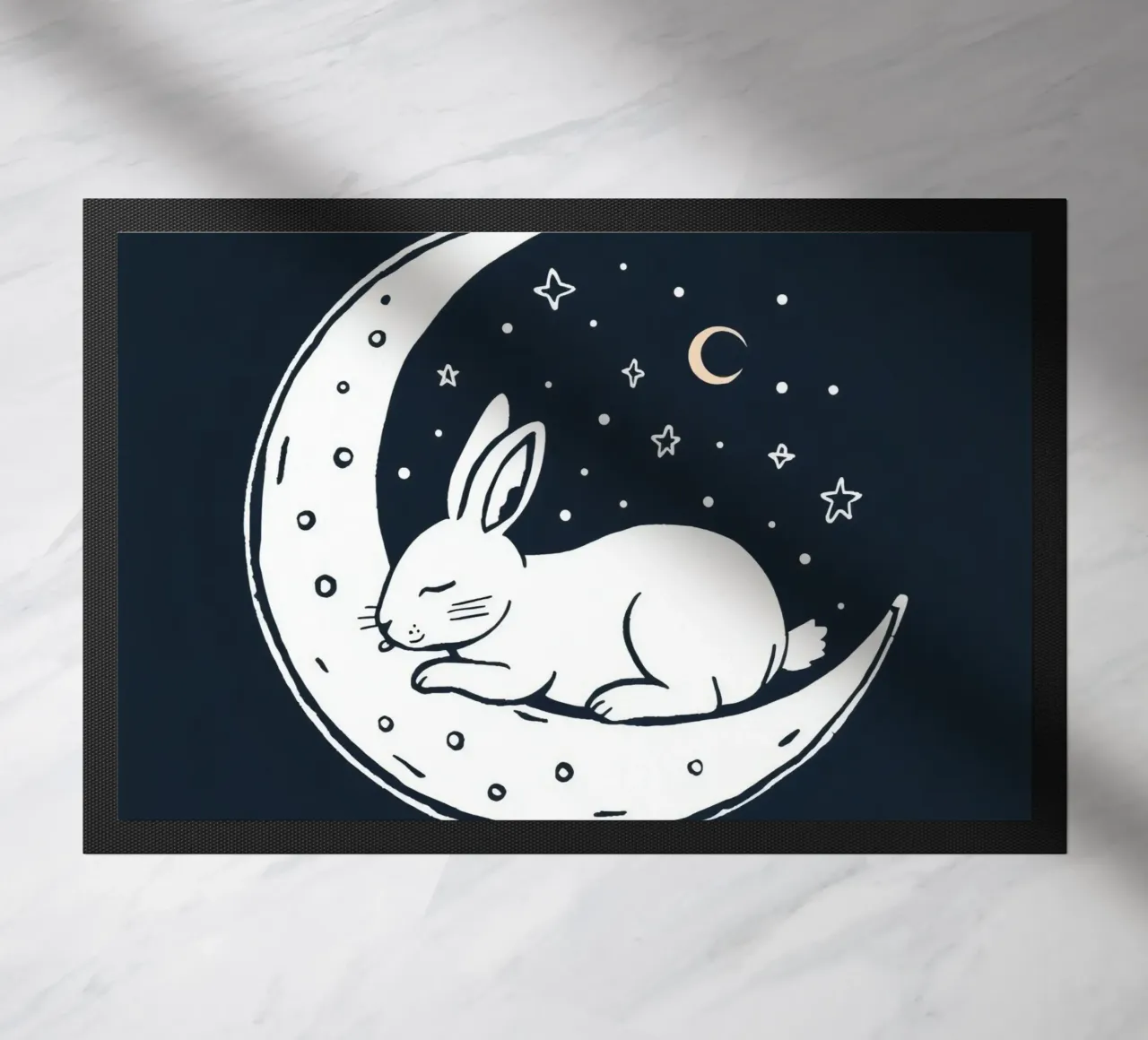 Lapin endormi reposant sur un croissant de lune entouré d'étoiles paillasson de DesignDoodle