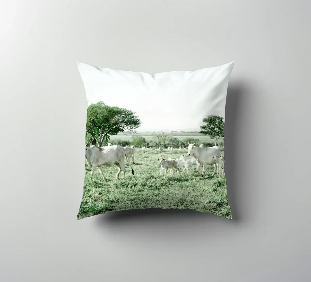 Mucche bianche in un campo verde cuscino da KISSA STUDIO