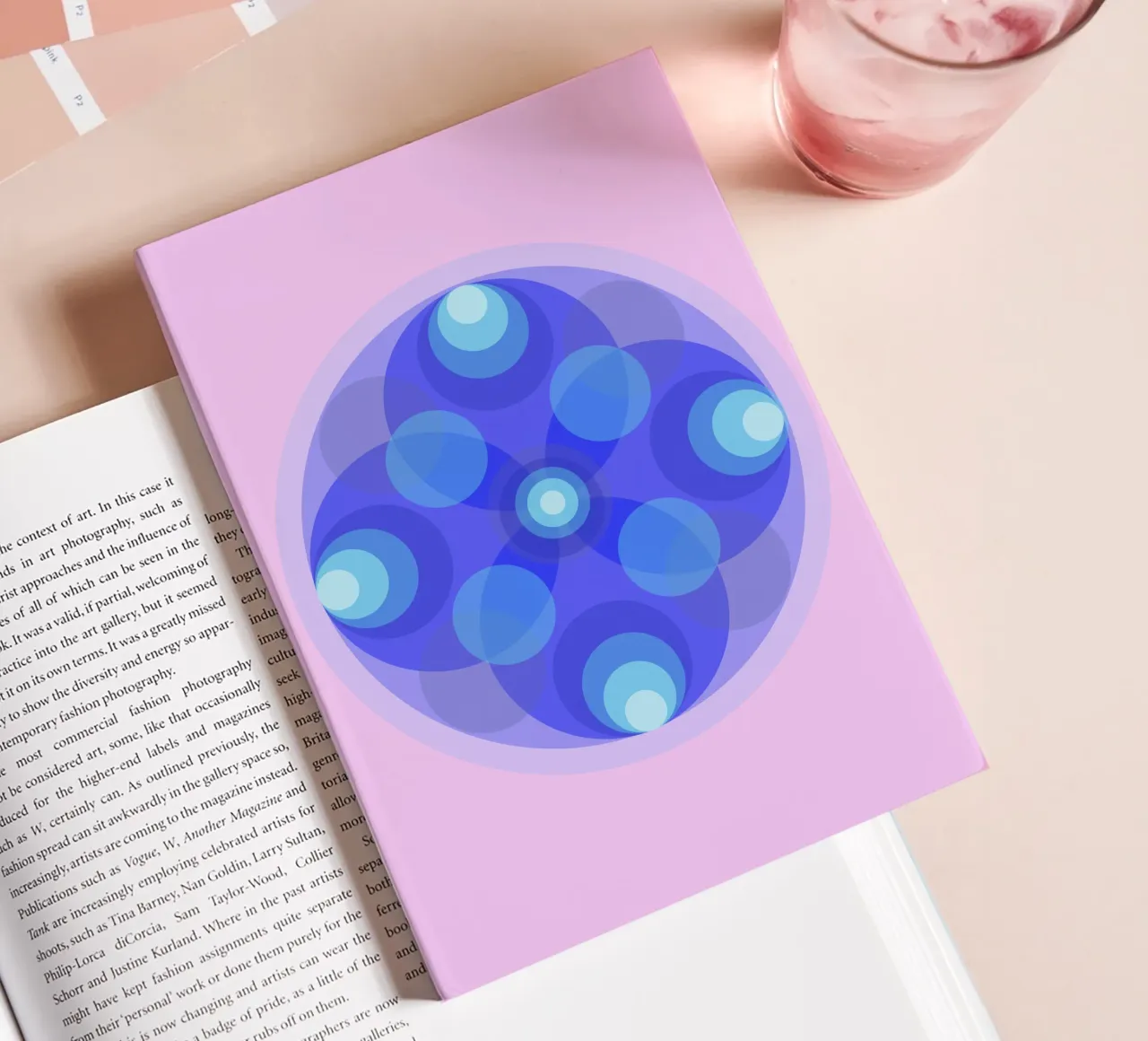 Blue abstract retro flower mandala in front of pink notebook by Lilou Art