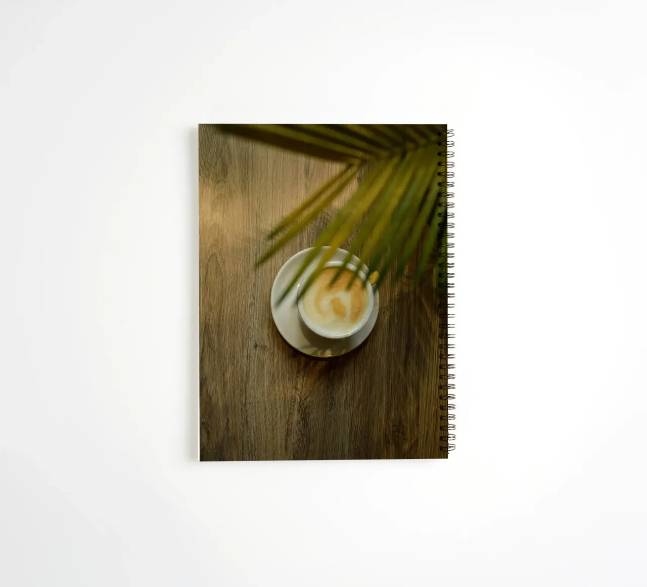 latte art coffee under leave spiral notebook by cofa home
