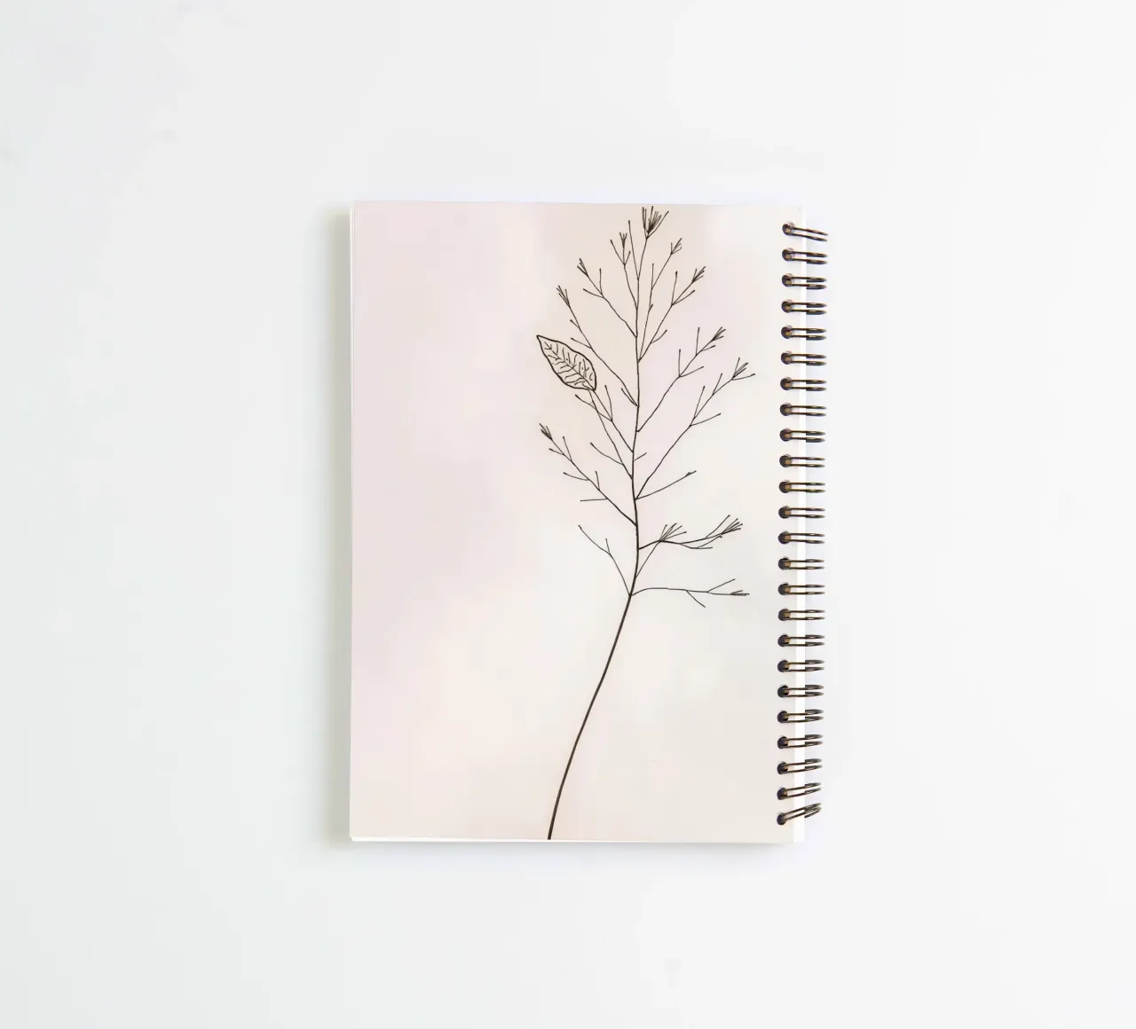Single minimal botanical branch, displaying a leaf spiral notebook by DesignDoodle