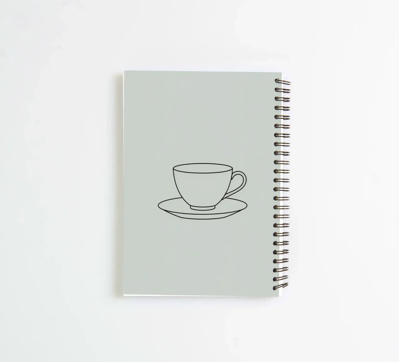 Semplice schizzo di una tazza da tè su un piattino esposto su un minimo diario ad anelli da DesignDoodle