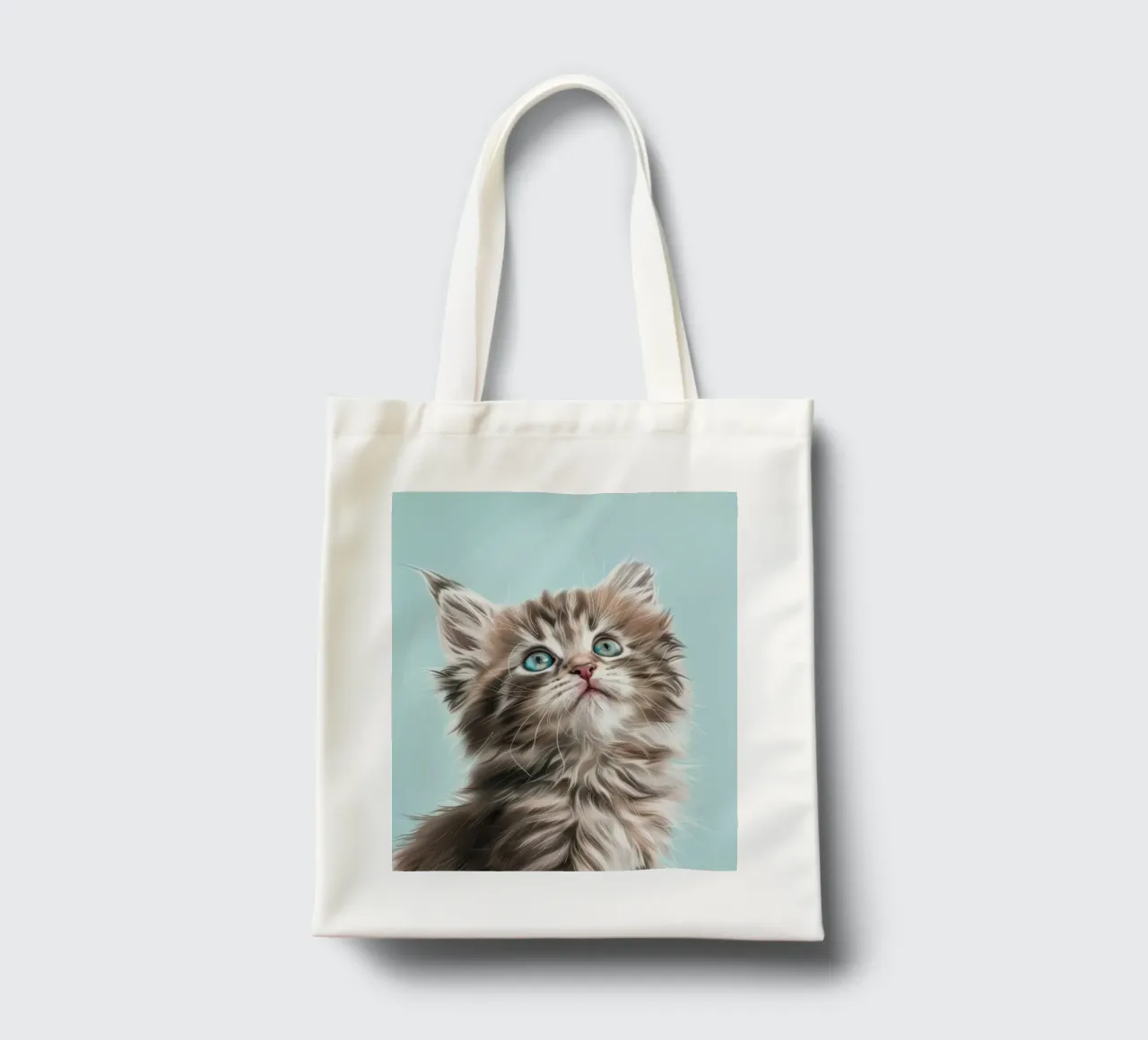 Adorable chaton en peluche regardant vers le haut avec des yeux bleus saisissants tote bag de DesignDoodle