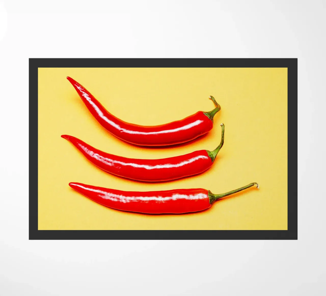 Piment rouge sur surface jaune paillasson de Bilderwelt - Kunst für die Wand