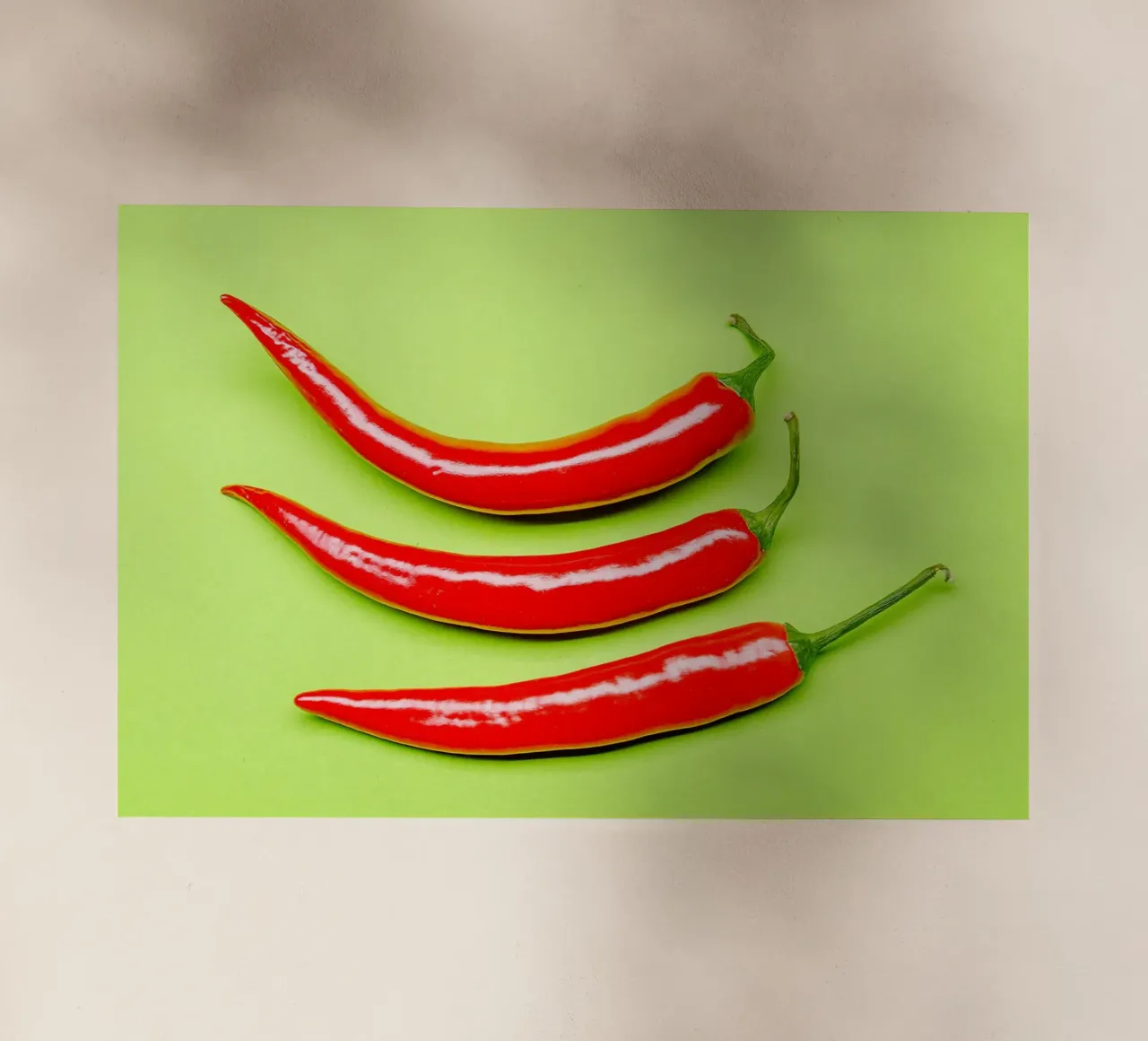 Three red chilli peppers on a green surface backlit film by Bilderwelt - Kunst für die Wand