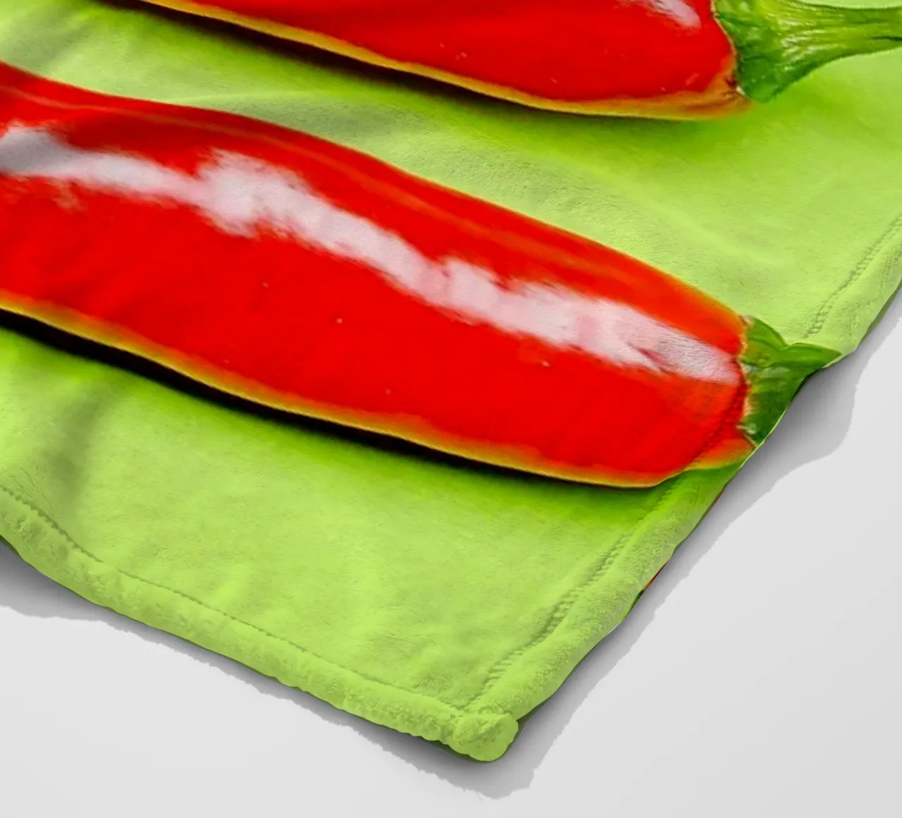 Three red chilli peppers on a green surface fleece blanket by Bilderwelt - Kunst für die Wand