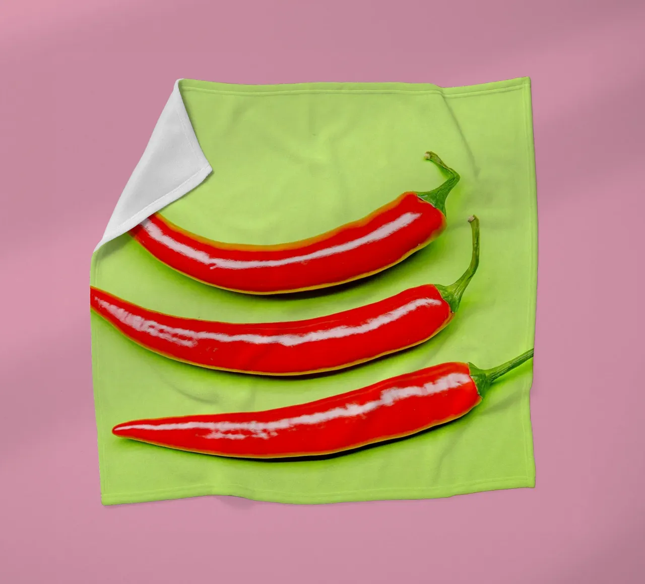 Three red chilli peppers on a green surface fleece blanket by Bilderwelt - Kunst für die Wand