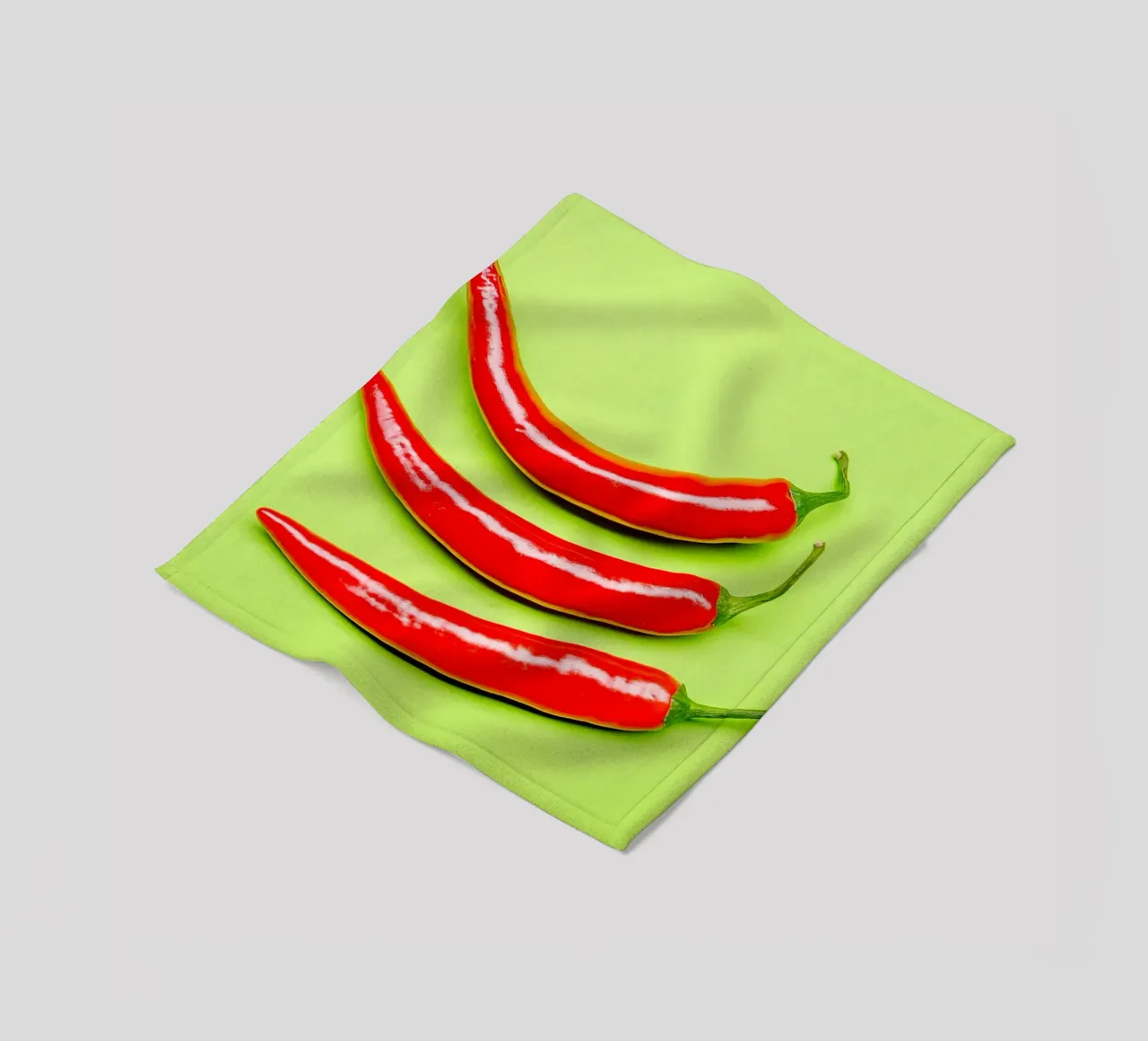 Three red chilli peppers on a green surface fleece blanket by Bilderwelt - Kunst für die Wand