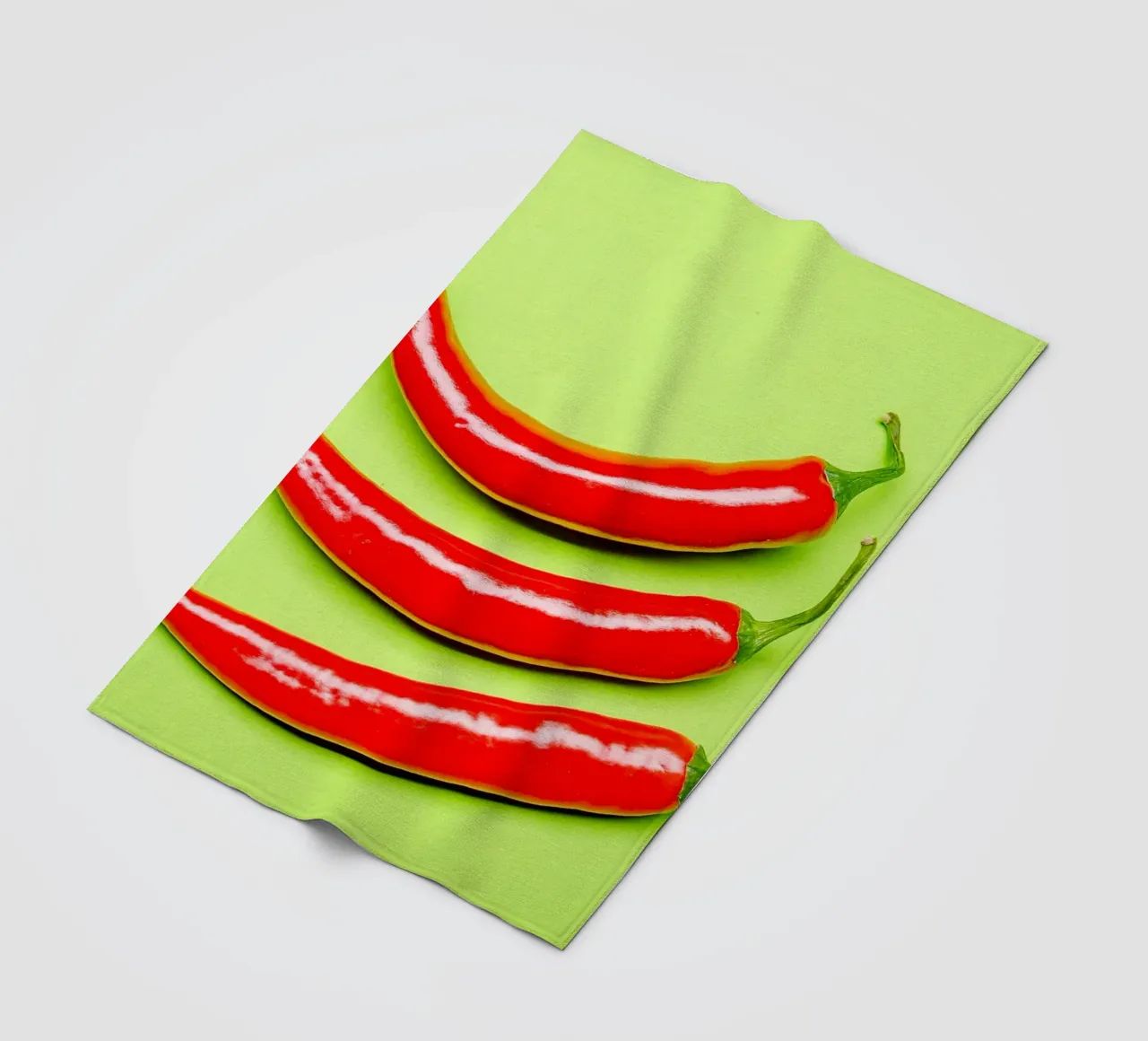Three red chilli peppers on a green surface fleece blanket by Bilderwelt - Kunst für die Wand