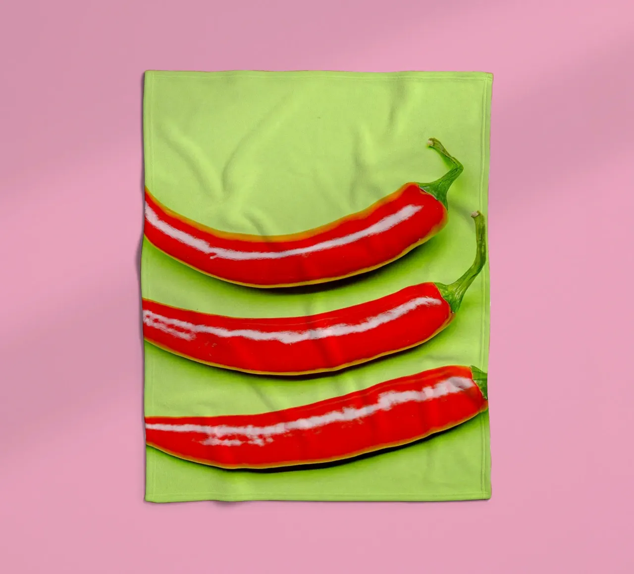 Three red chilli peppers on a green surface fleece blanket by Bilderwelt - Kunst für die Wand