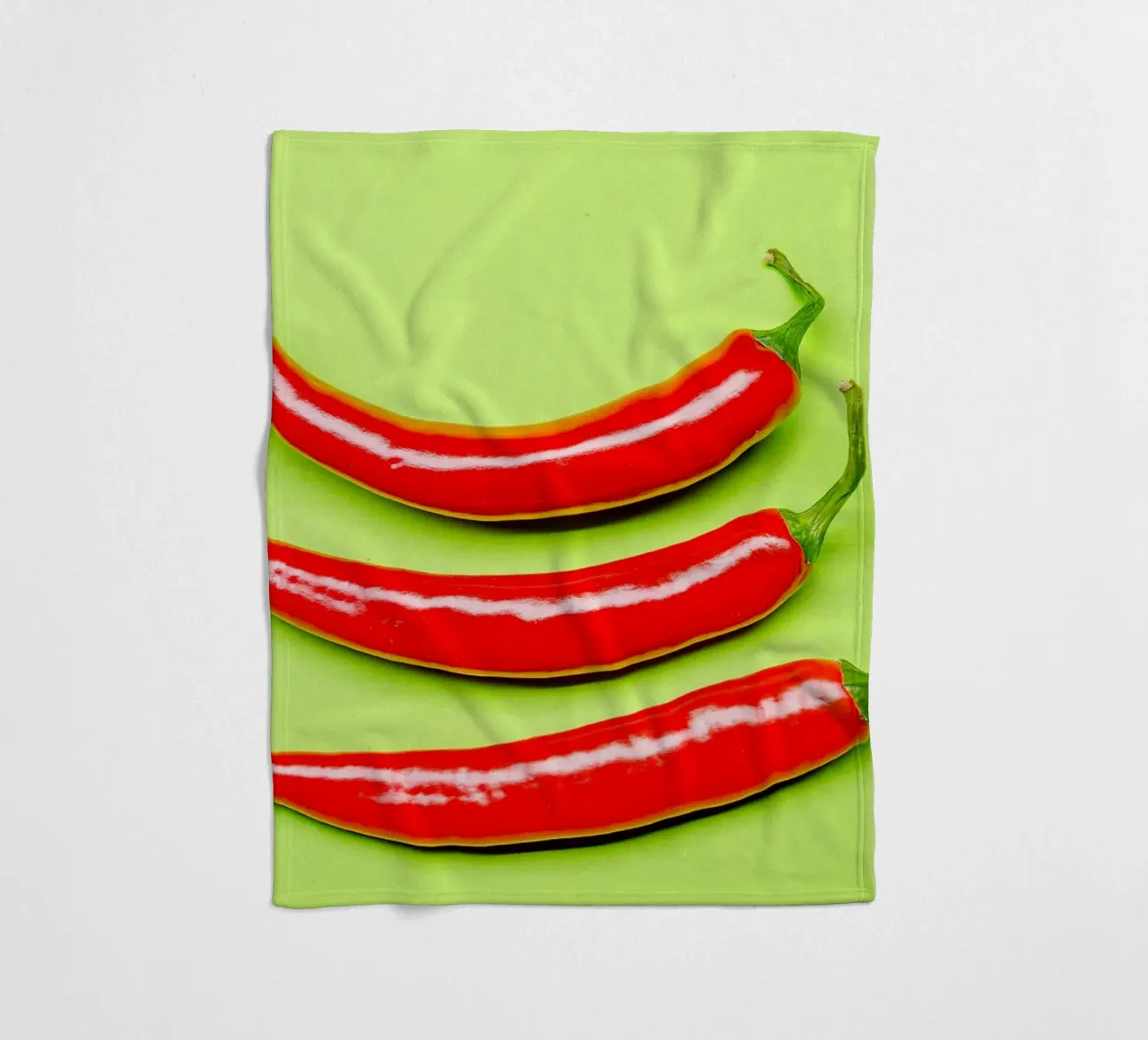 Three red chilli peppers on a green surface fleece blanket by Bilderwelt - Kunst für die Wand