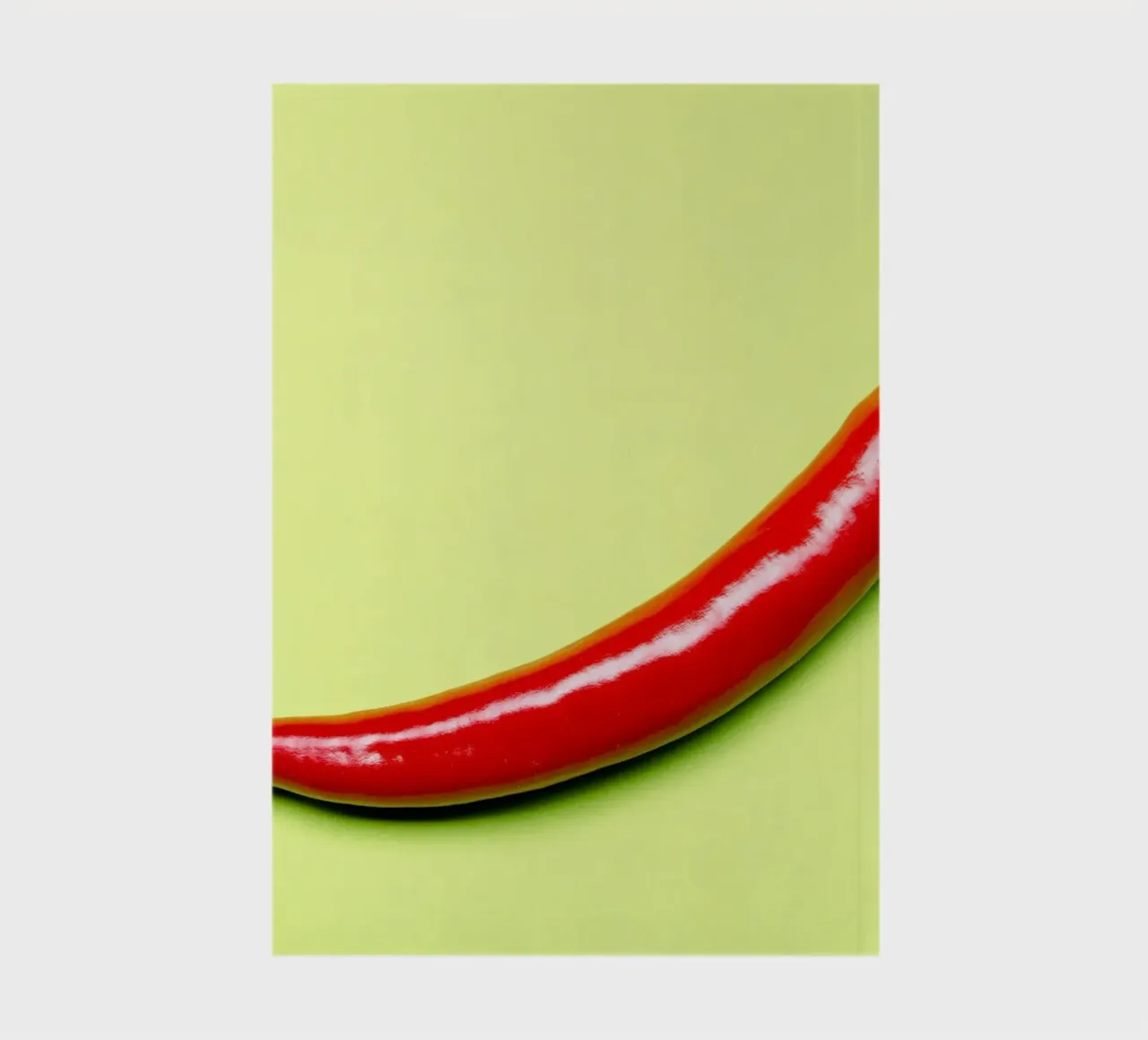 Red chilli pepper on a green background notebook by Bilderwelt - Kunst für die Wand