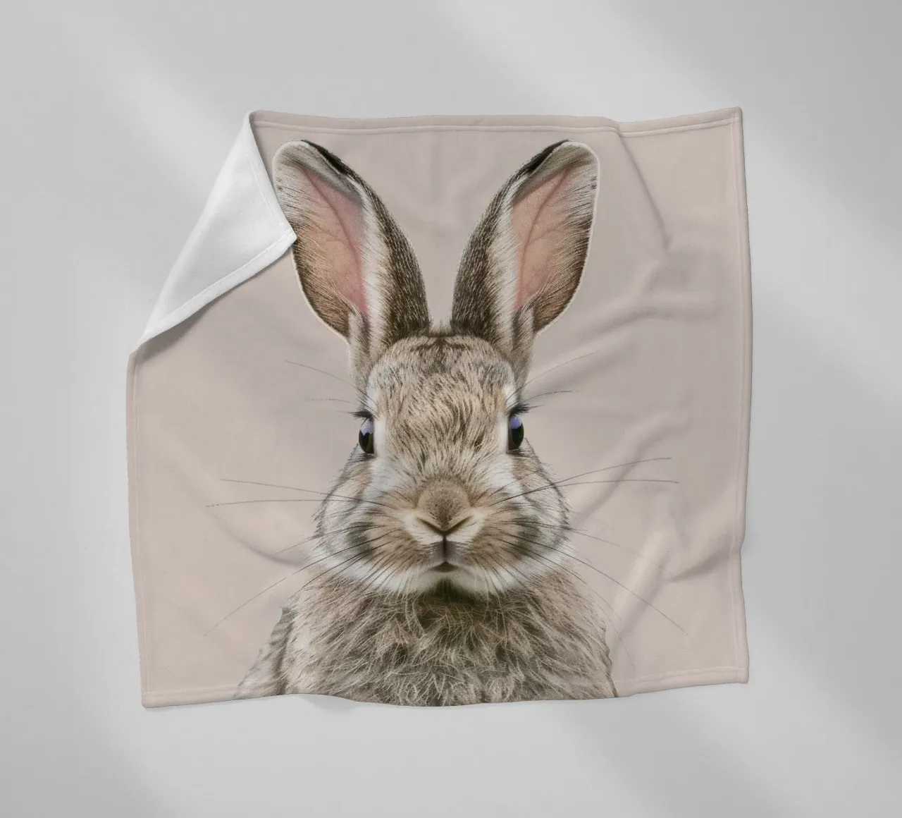 Fluffy rabbit with expressive eyes against a neutral art fleece blanket by DesignDoodle