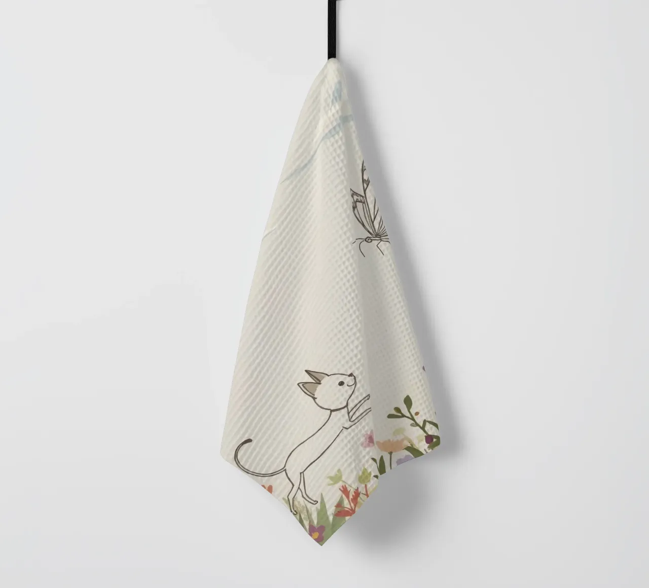 Katze jagt Schmetterling in einer blühenden Wiese unter einem weichen Himmel Geschirrtuch von DesignDoodle