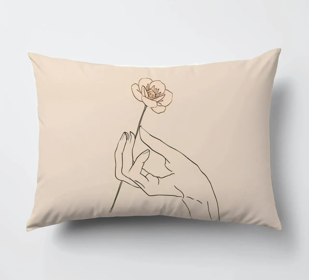 Elegant hand holding delicate flower against a soft beige decorative cushion by DesignDoodle
