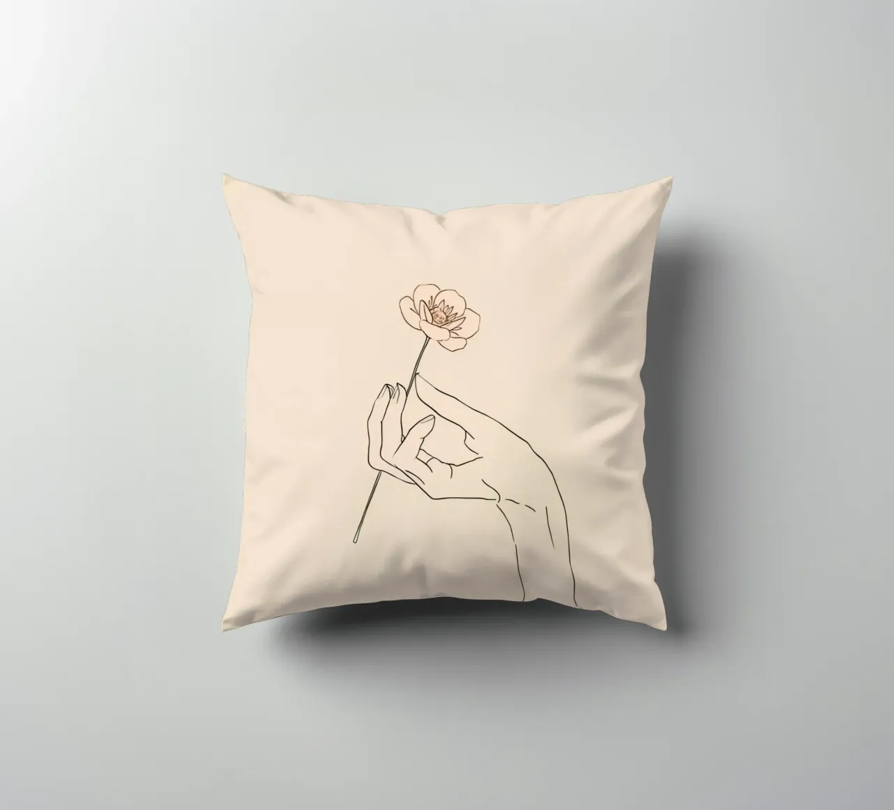 Elegant hand holding delicate flower against a soft beige decorative cushion by DesignDoodle