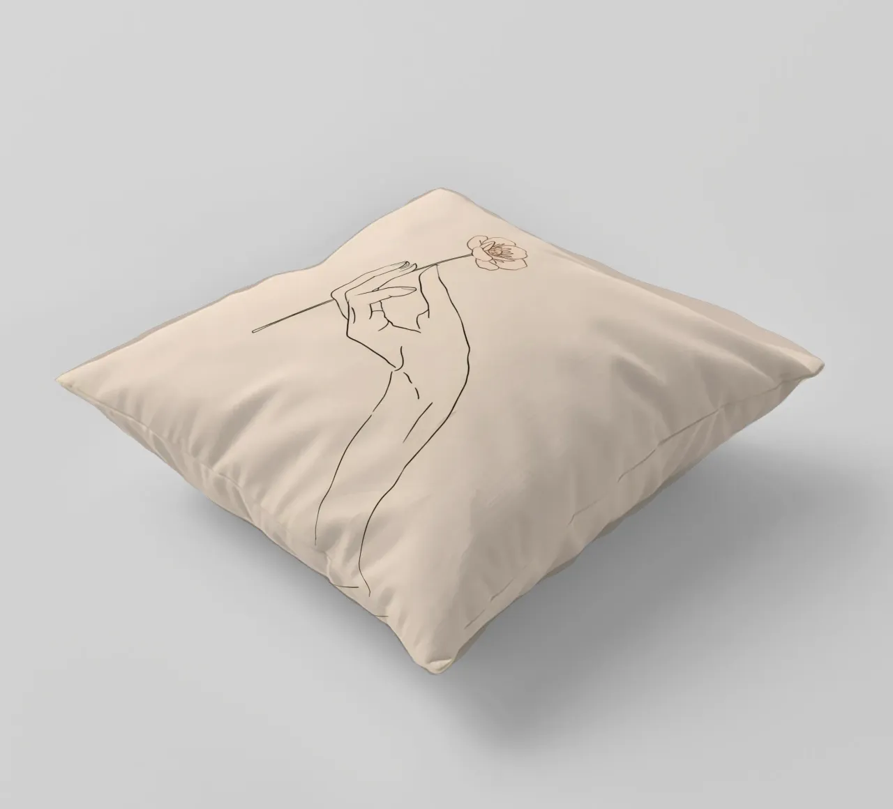 Elegant hand holding delicate flower against a soft beige decorative cushion by DesignDoodle