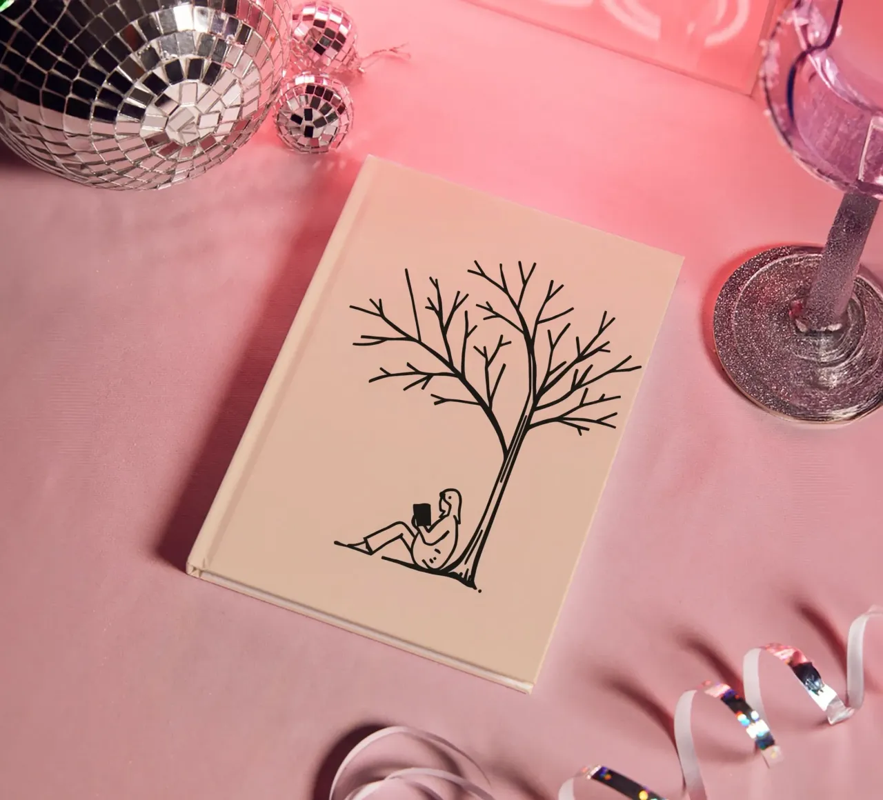 Person reading a book under a bare tree on a warm afternoon notebook by DesignDoodle