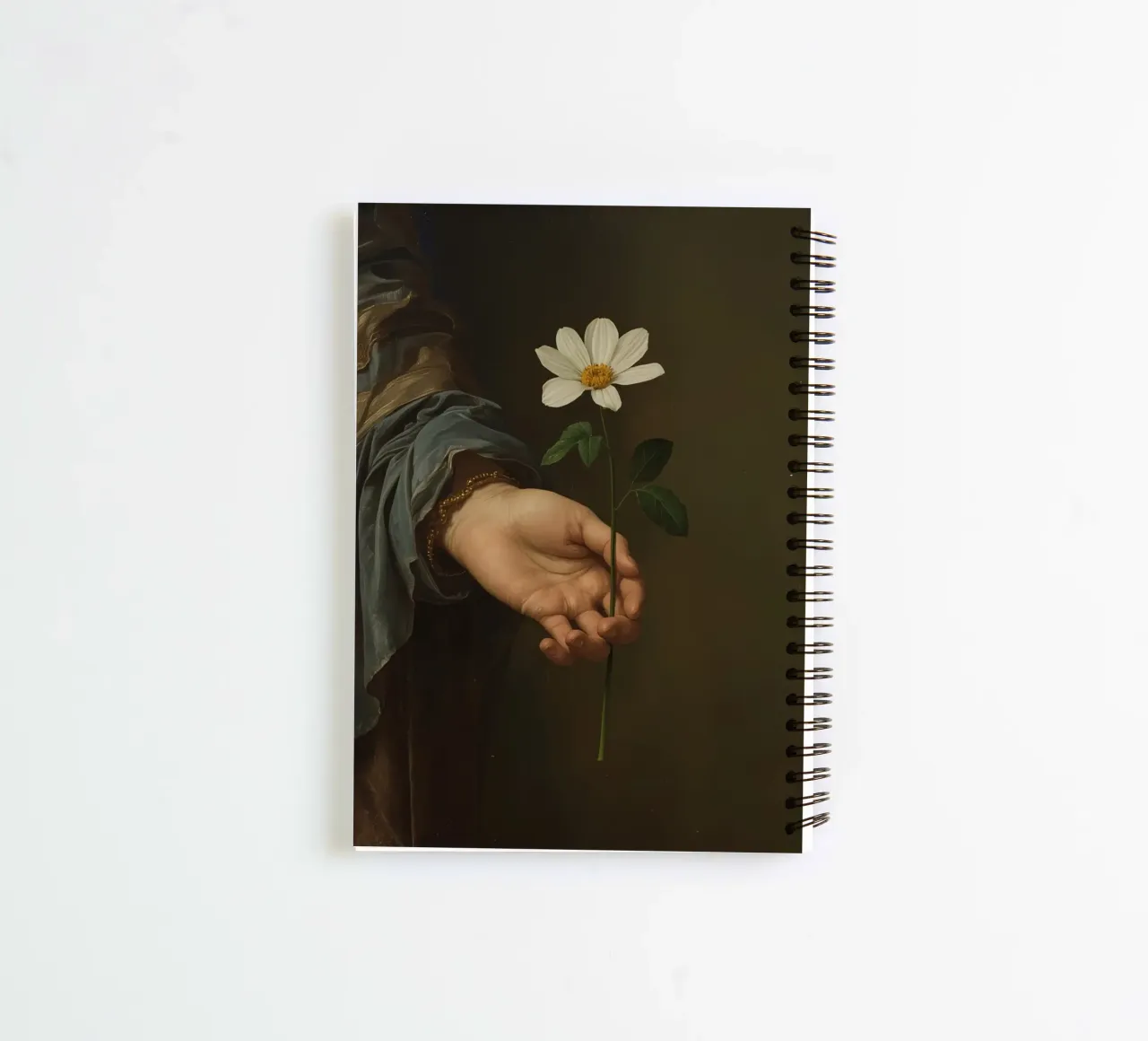 Mano che regge un fiore bianco in una luce soffusa con diario ad anelli da DesignDoodle
