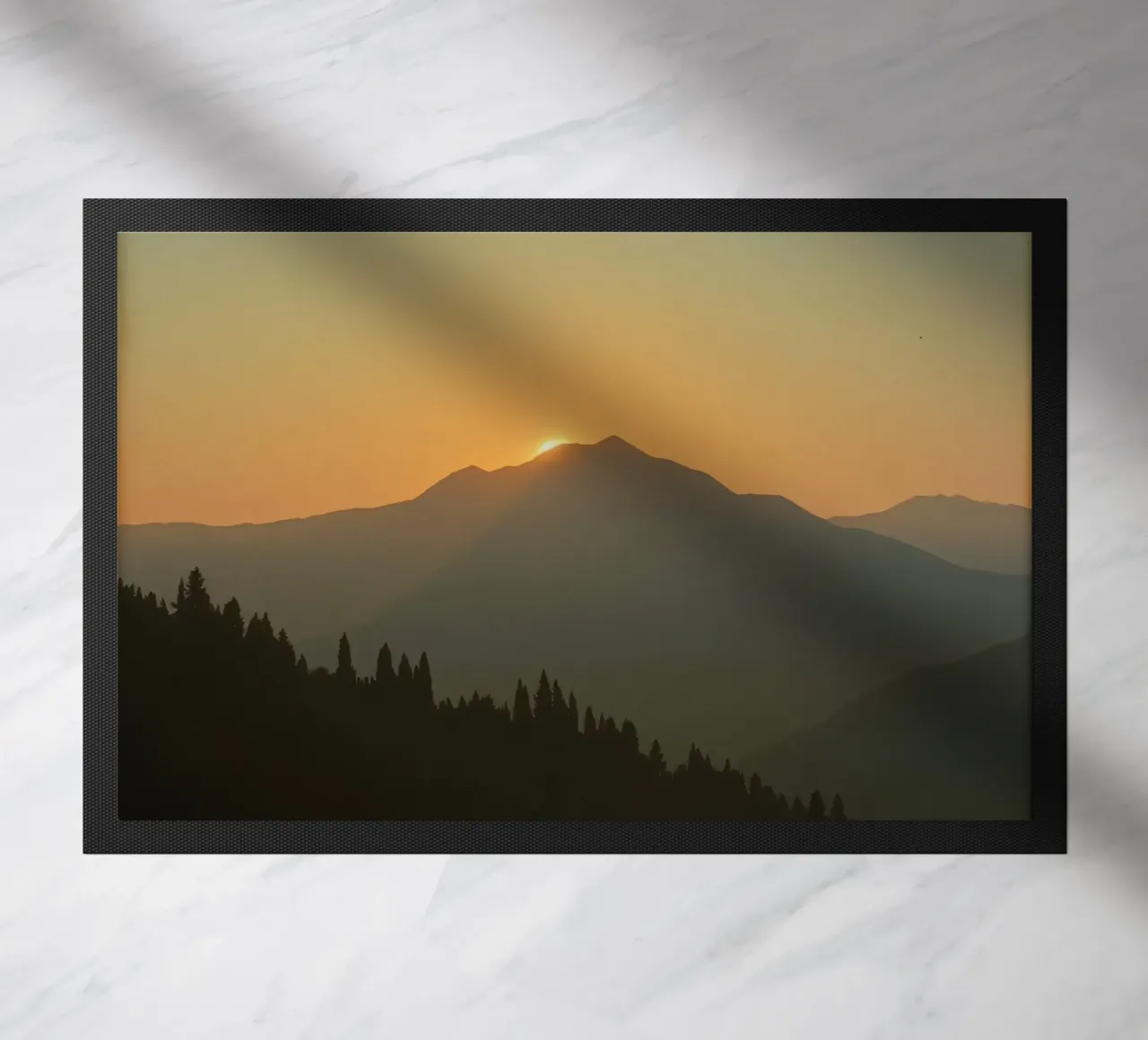 Sunset casting shadows over mountains and pine trees doormat by DesignDoodle