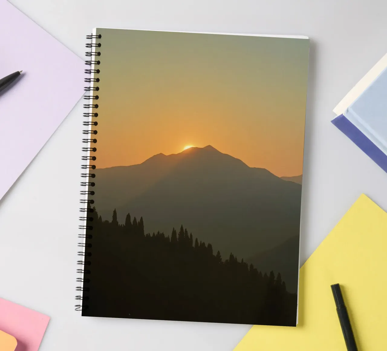 Zonsondergang werpt schaduwen over bergen en pijnbomen notitieboek met spiraal van DesignDoodle