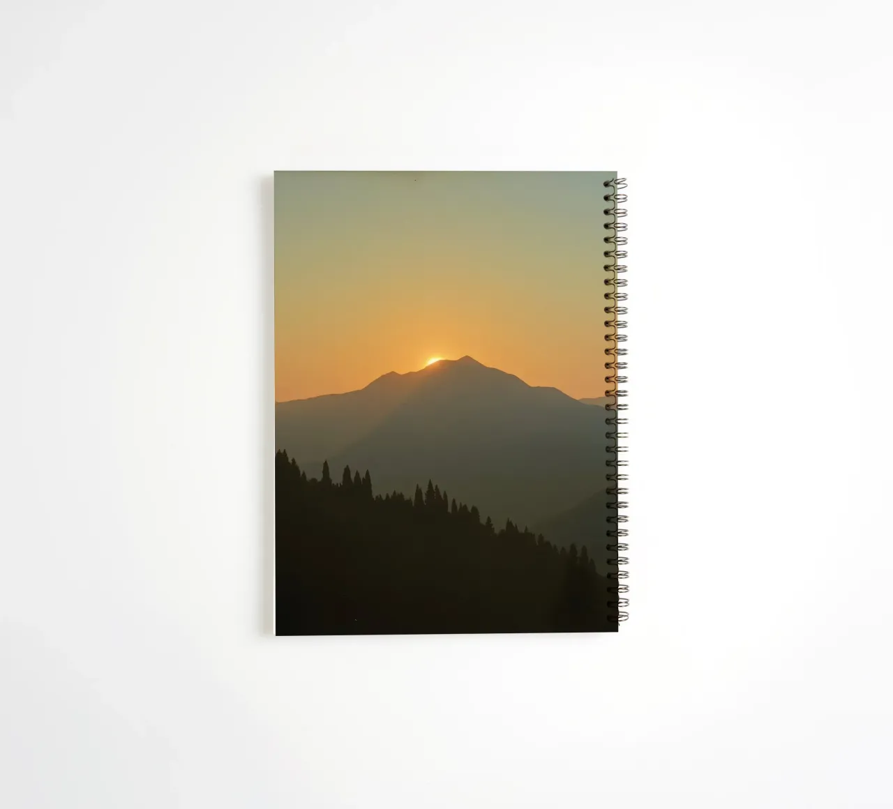 Zonsondergang werpt schaduwen over bergen en pijnbomen notitieboek met spiraal van DesignDoodle