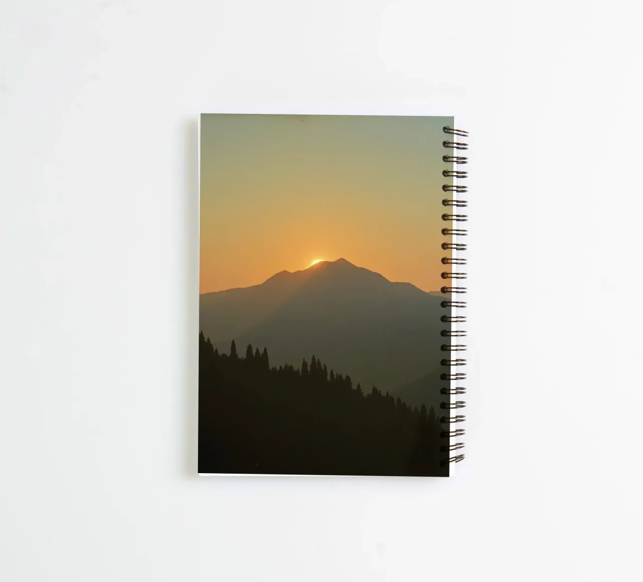 Zonsondergang werpt schaduwen over bergen en pijnbomen notitieboek met spiraal van DesignDoodle