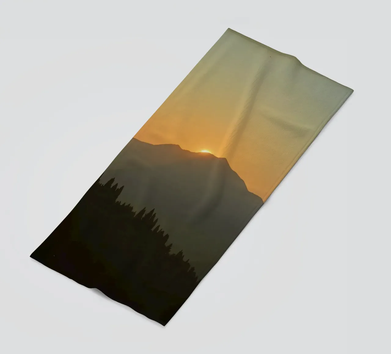 Zonsondergang werpt schaduwen over bergen en pijnbomen strandhanddoek van DesignDoodle