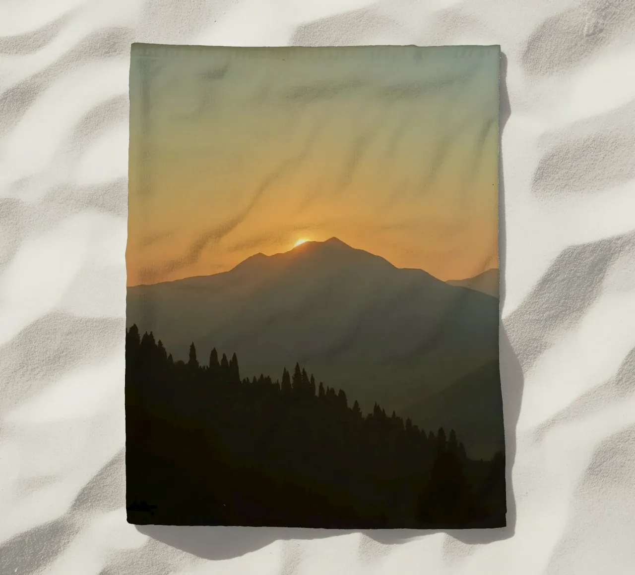 Zonsondergang werpt schaduwen over bergen en pijnbomen strandhanddoek van DesignDoodle