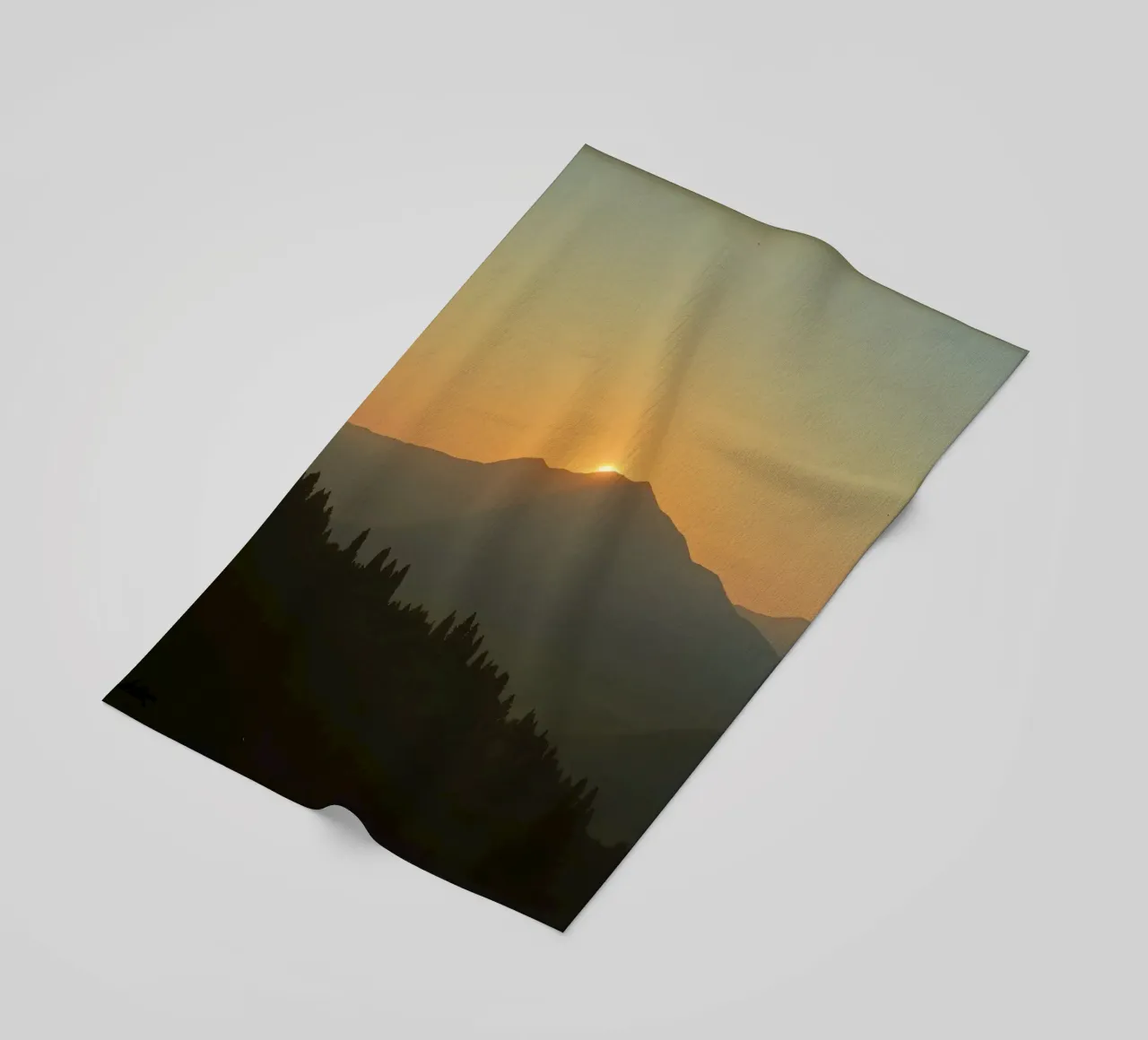 Zonsondergang werpt schaduwen over bergen en pijnbomen strandhanddoek van DesignDoodle
