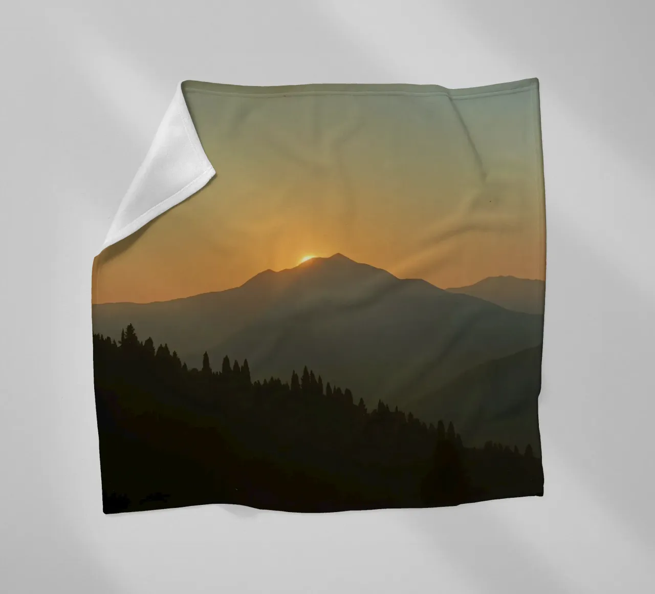 Sunset casting shadows over mountains and pine trees fleece blanket by DesignDoodle