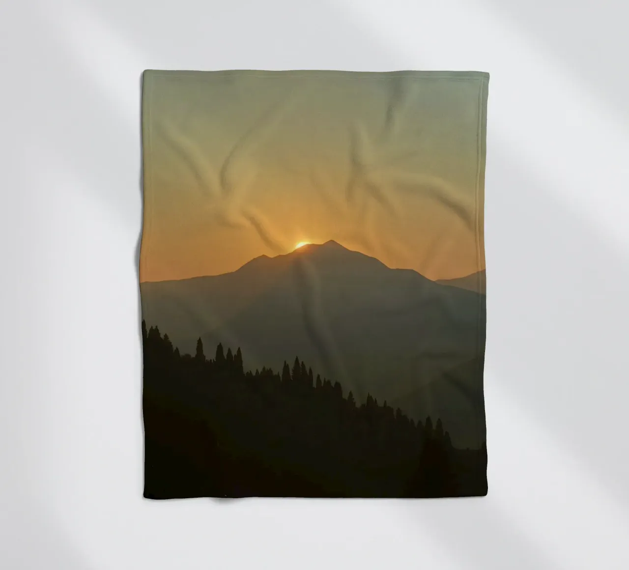 Sunset casting shadows over mountains and pine trees fleece blanket by DesignDoodle
