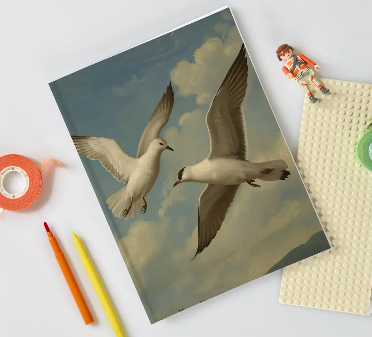 Two seagulls in mid-flight against a backdrop of clouds notebook by DesignDoodle