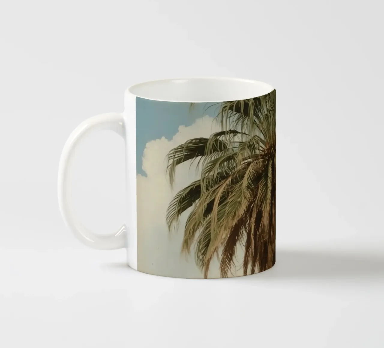 Palma alta con cielo blu e nuvole soffici in una luce calda. tazza in ceramica da DesignDoodle