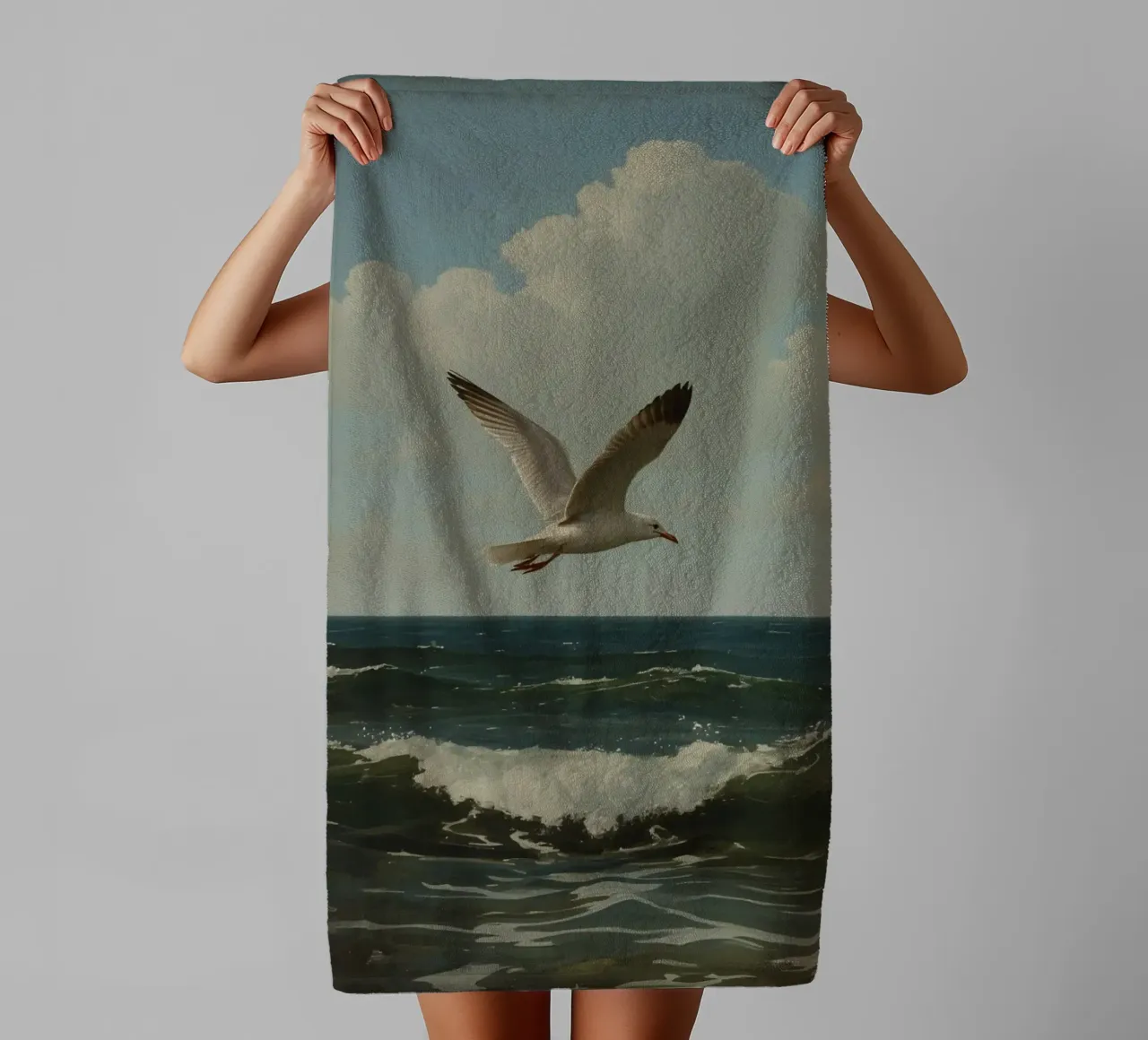 Seagull gliding over ocean waves under a partly cloudy sky towel by DesignDoodle